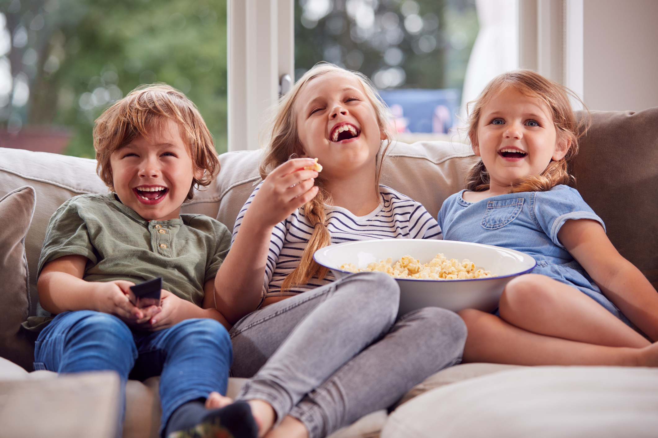Ba Đứa Trẻ Ngồi Trên Ghế Sofa Ở Nhà Cười Và Xem TV Với Bỏng Ngô